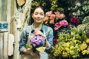 花屋で花を持っている女性の画像